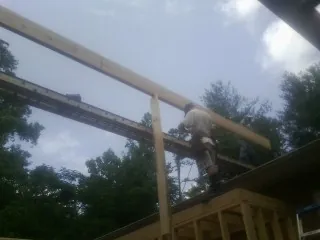 Carpenter setting a ridge beam over a new addition frame — Ice Dam Removal by Roofing Brothers in Newaygo