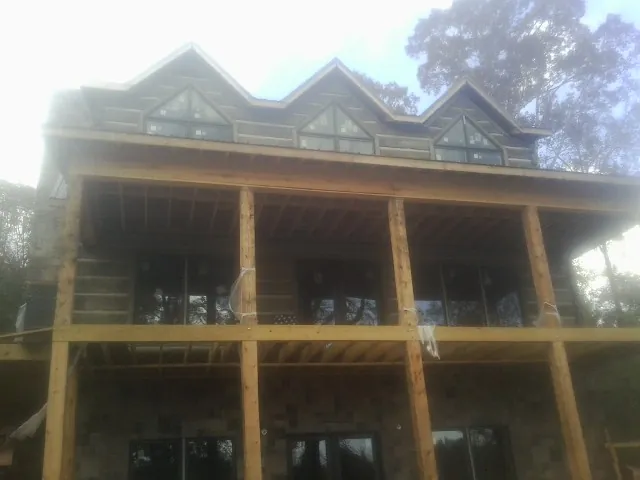 Dormers and porch framing on a large log home under construction — Roof Coating work by our crew in Newaygo