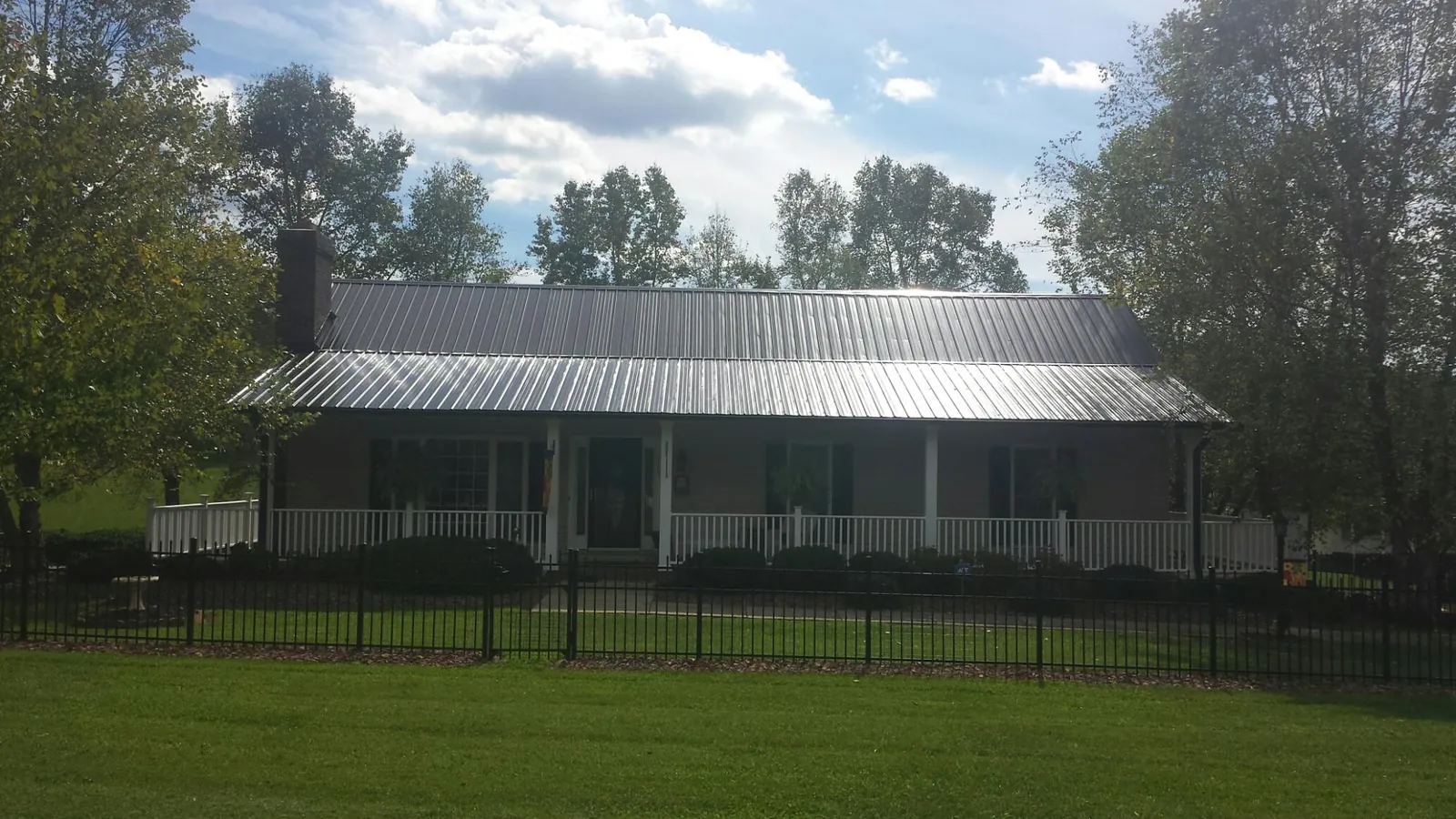 Gray metal roof on a brick ranch with a full width front porch — Gutter Guard Installation work by our crew in Newaygo